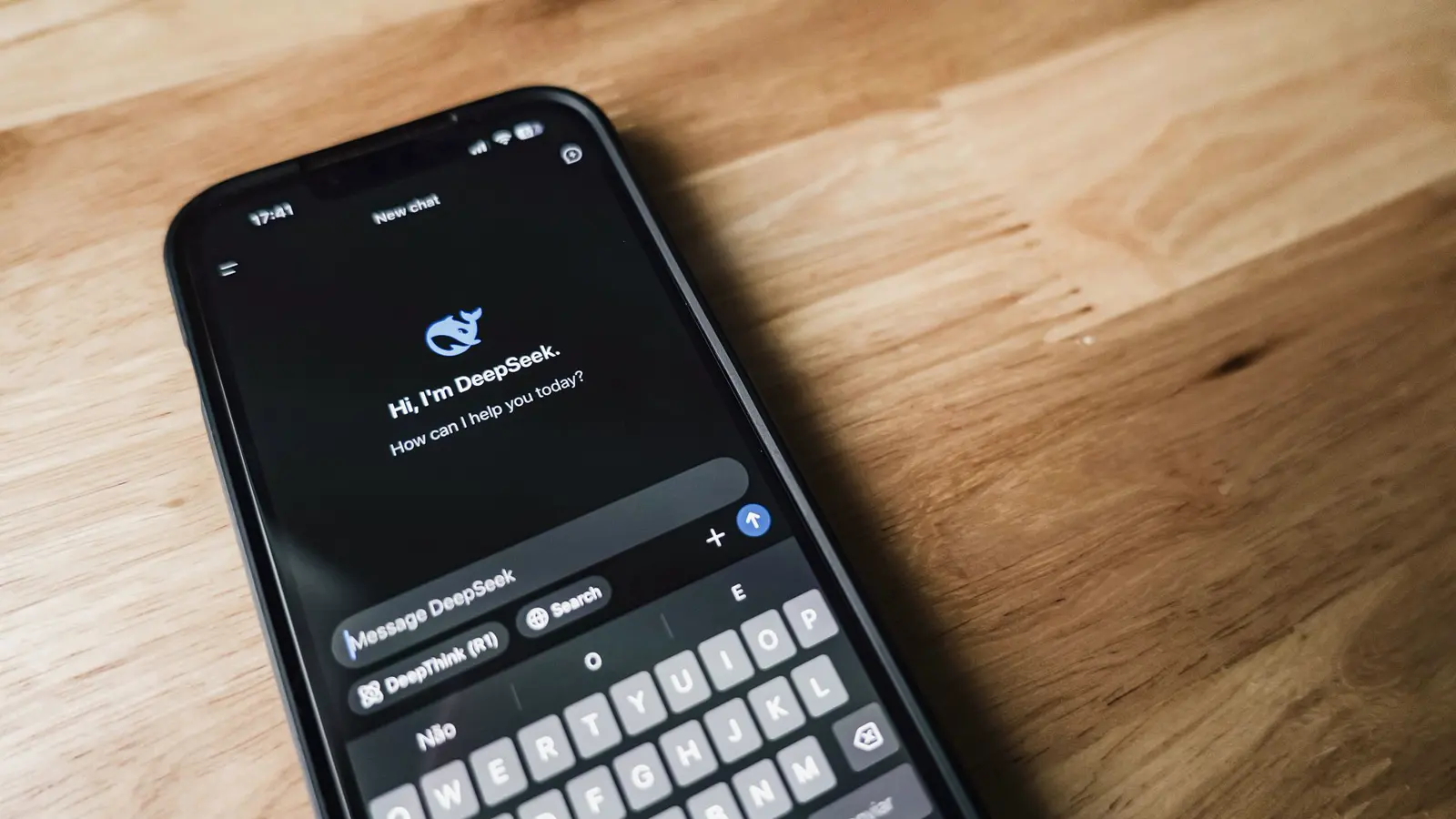 Ahşap masada yapay zekâ sohbet ekranı açık bir akıllı telefon